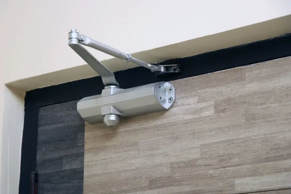 Door closer mechanism mounted above a door frame for smooth door operation.