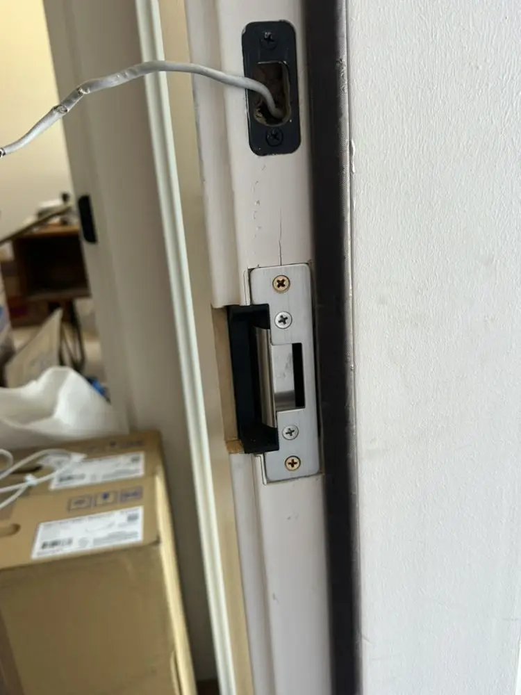 Lock mechanism installed into a door frame with wiring visible.